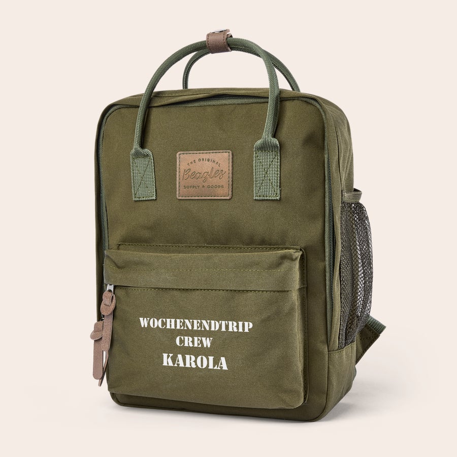 Rucksack personalisieren Grüner Rucksack mit dem Aufdruck "Wochenendtrip Crew Karola", den Sie mit einem Namen individualisieren können.
