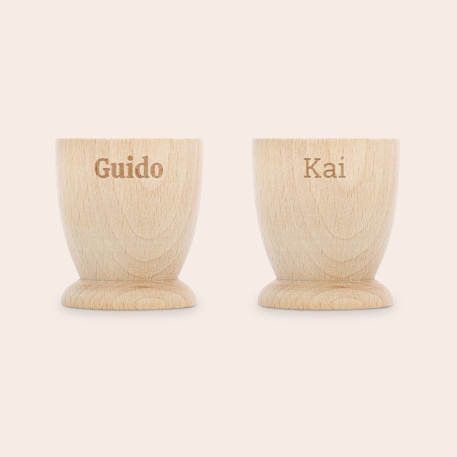 Eierbecher personalisiert Zwei personalisierte Eierbecher aus hellem Buchenholz mit den gravierten Namen Guido und Kai. Mach das Frühstück unvergesslich.