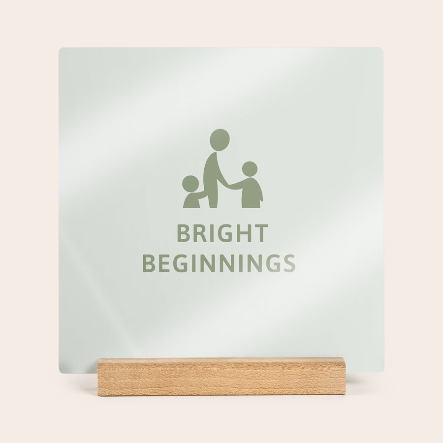 Carreaux photo personnalisés Tuile photo carrée en bois personnalisée imprimée avec un design "BRIGHT BEGINNINGS" et un pictogramme familial, sur un support en bois clair.