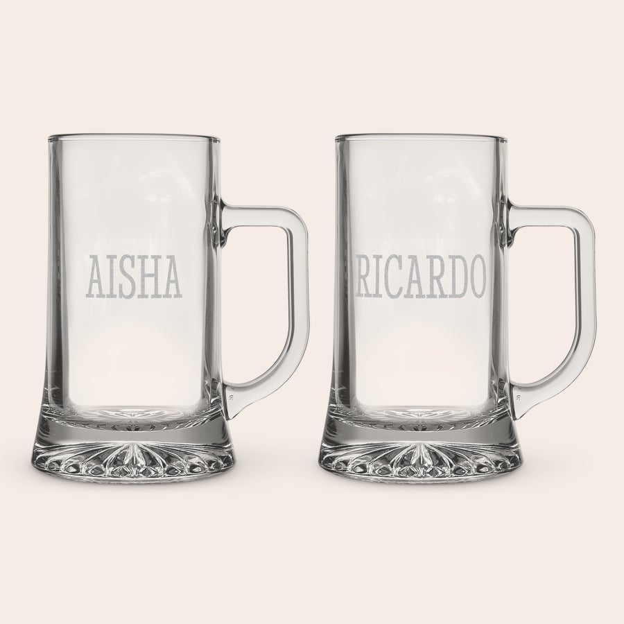 Glass Tankard Two personalised glass tankards, one engraved with AISHA and the other with RICARDO, each with a crystal base.