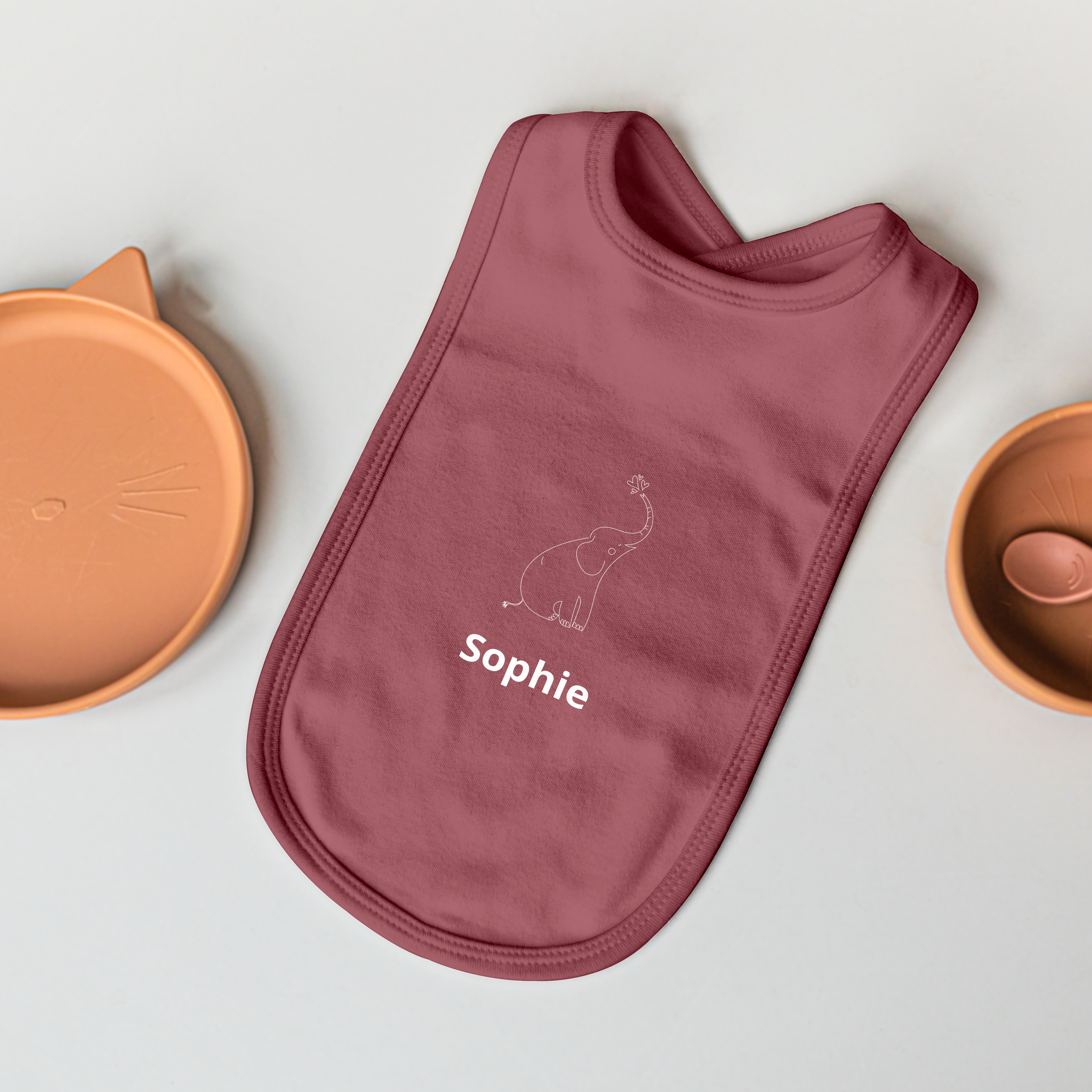 En personlig smekke i mørkerosa med navnet Sophie og et trykt elefantmotiv.