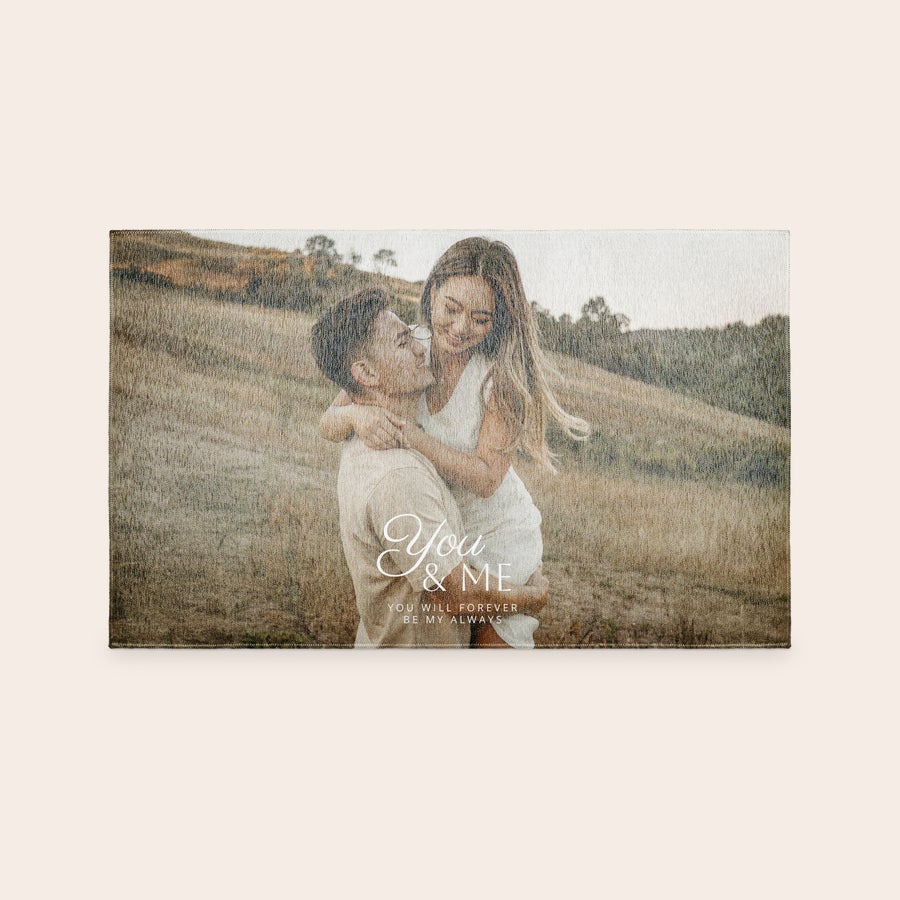 Tapete estampado Um tapete personalizado com foto de casal abraçado em um campo e texto "You & Me" impresso, tornando a casa única.