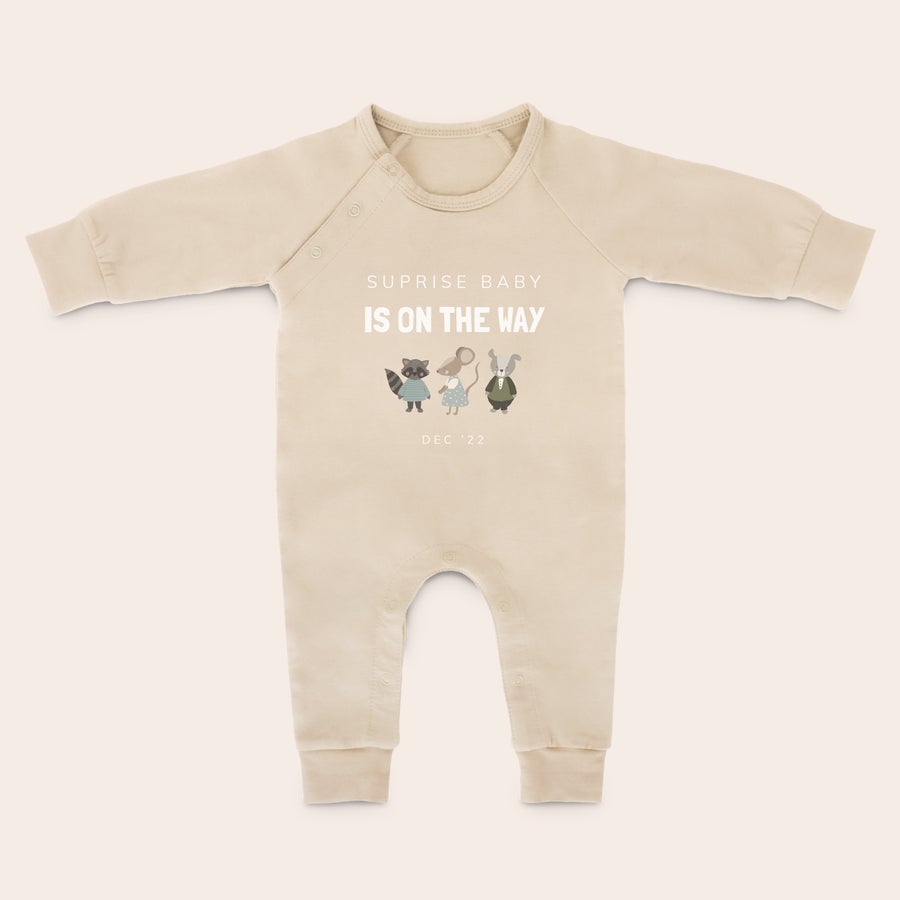 Baby lekedrakt med trykk Beige sparkedress med trykt illustrasjon av dyr og teksten "SUPRISE BABY IS ON THE WAY DEC '22" for å strekke og sparke med lubne ben.