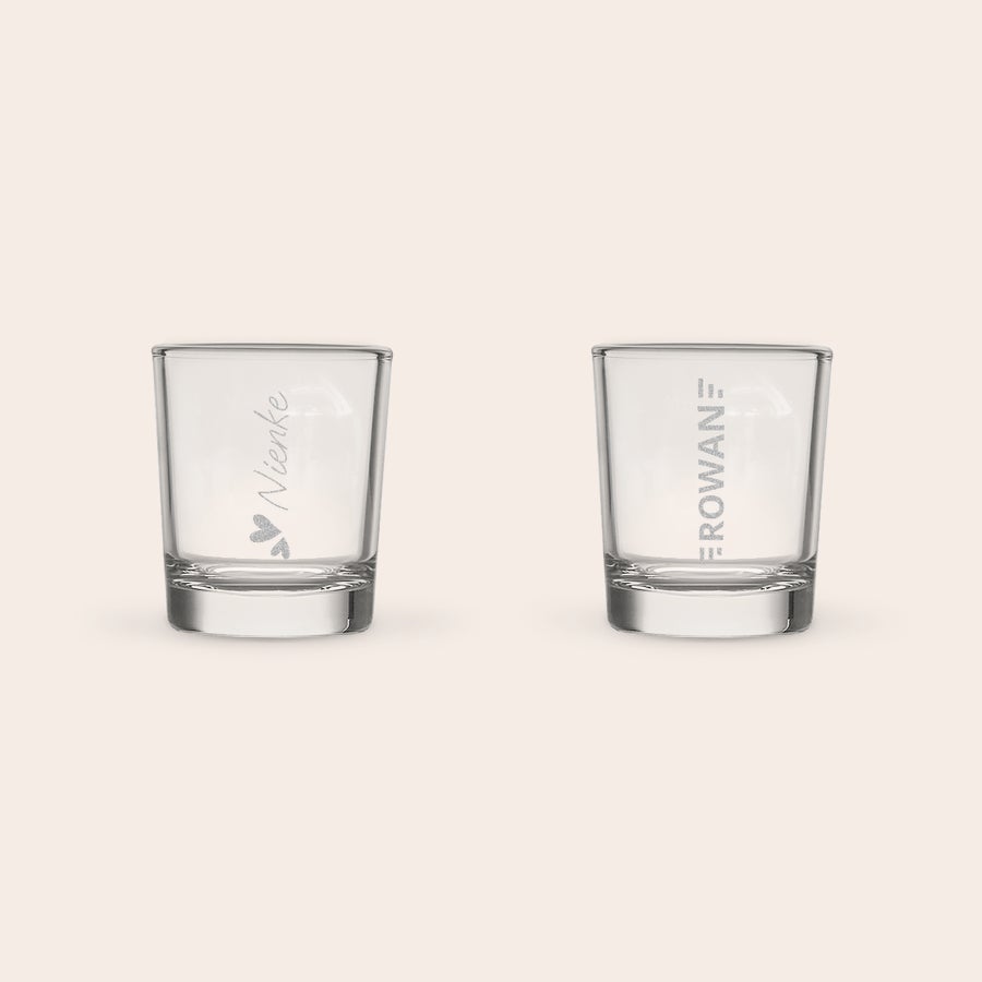 Shotglas graveren Twee gegraveerde shotglazen met naam. Het linker glas toont "Nienke" en harten, het rechter "ROWAN".