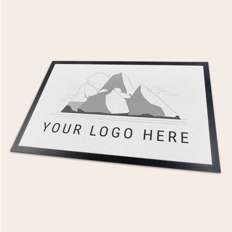Personlig dørmatte En unik personlig dørmatte med trykt fjellmotiv og tekst Your Logo Here, tilpasses med eget design.