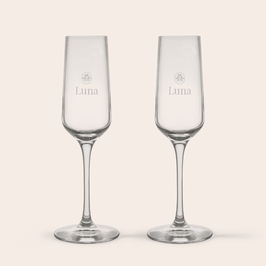 Pahar - Șampanie Două pahare de șampanie personalizate din cristal, gravate cu numele "Luna" și un simbol floral, ideale pentru un toast special.