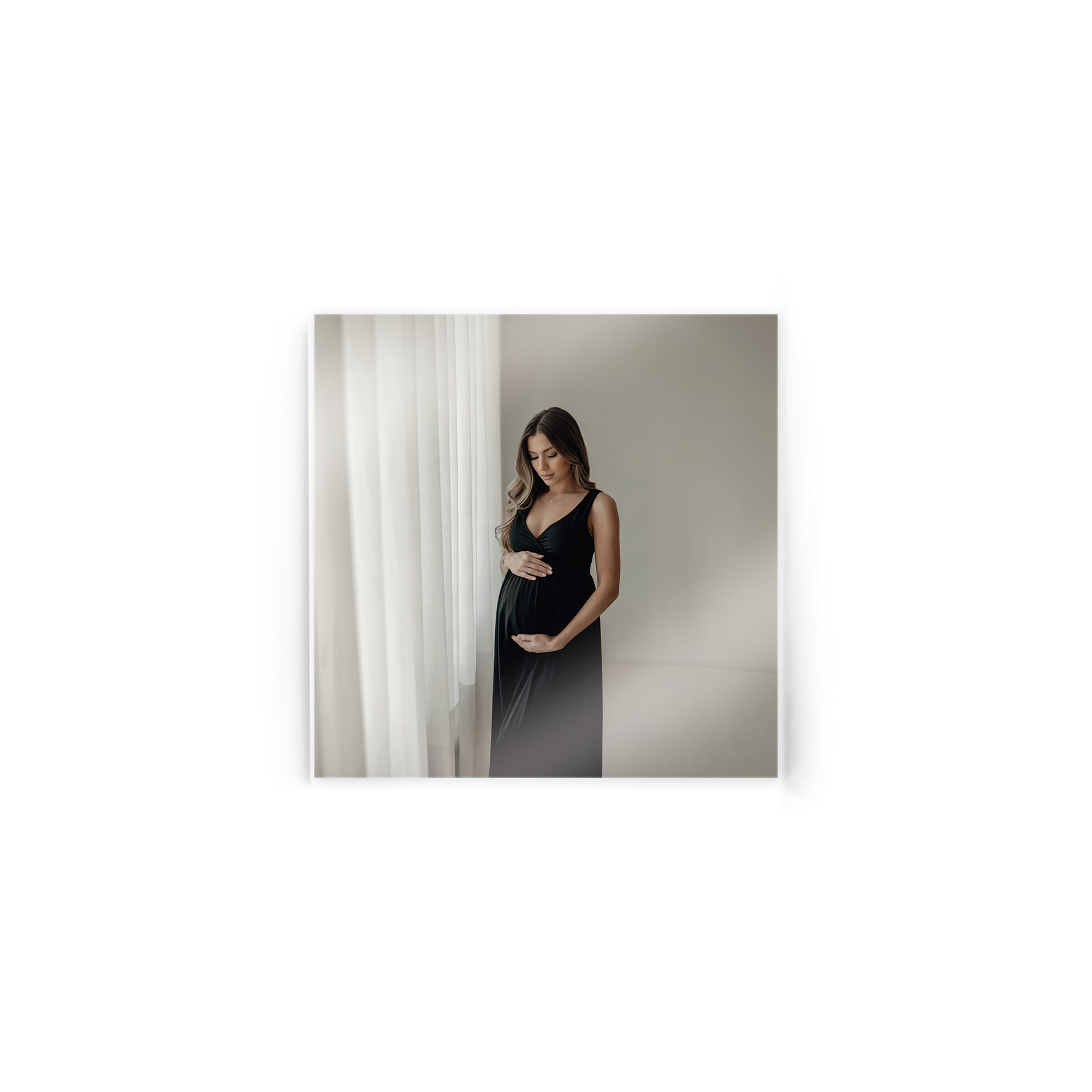 Foto auf Acrylglas mit Bild einer schwangeren Frau in schwarzem Kleid, die ihren Bauch hält.