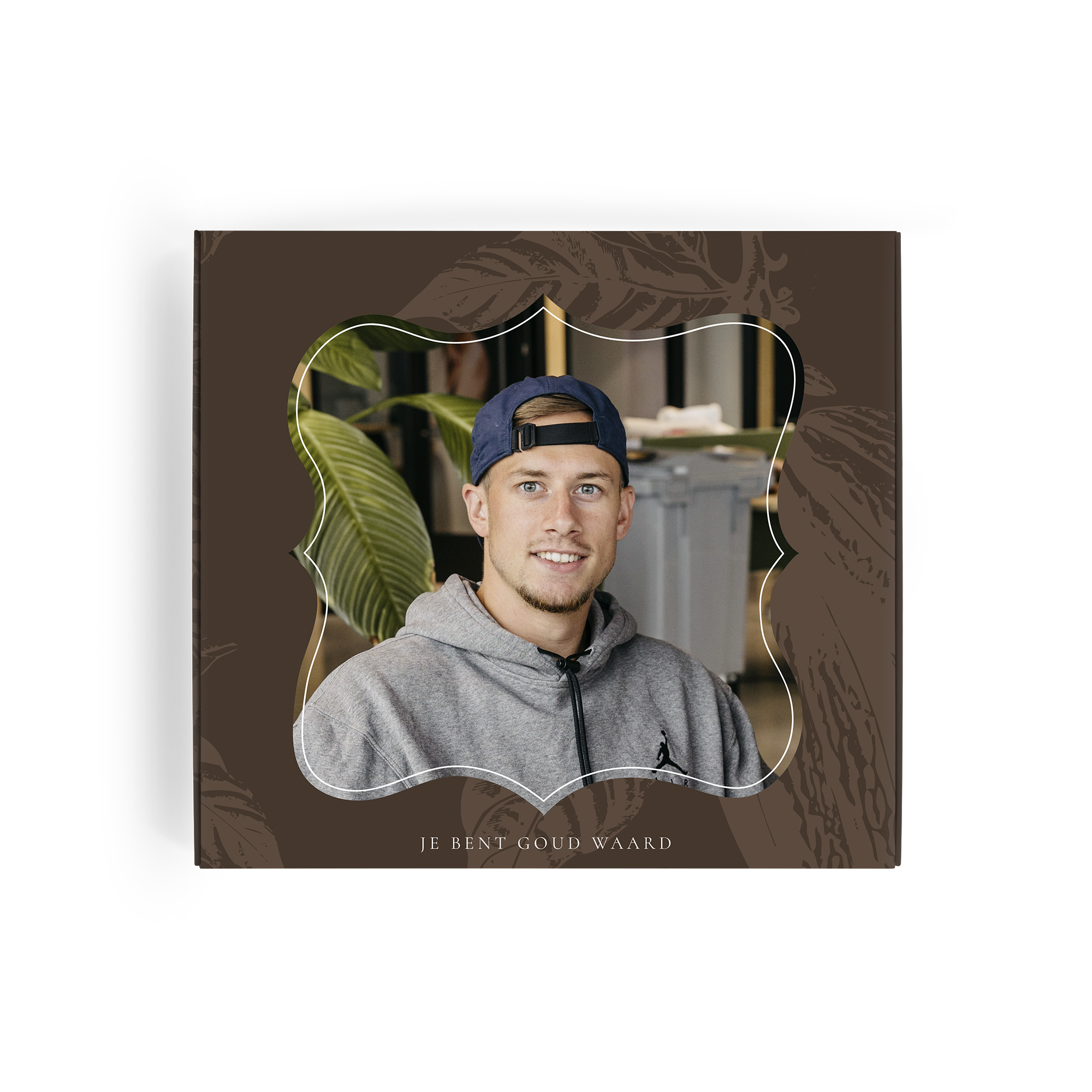 Gepersonaliseerde Milka giftbox met foto van een lachende man in een blauwe pet en grijs vest en de tekst "JE BENT GOUD WAARD" bedrukt op de doos.