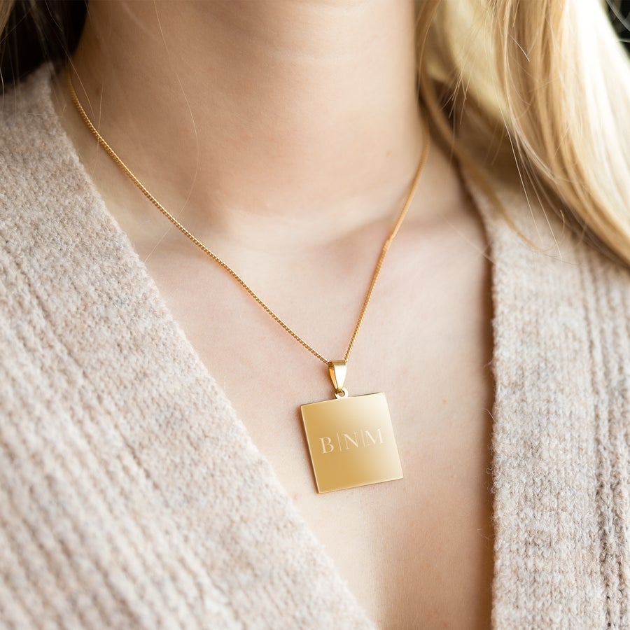 Necklace with square pendant Gold-plated square pendant with the initial B N M engraved, worn on a fine chain. Give a beautiful square engraved pendant with a name as a gift.
