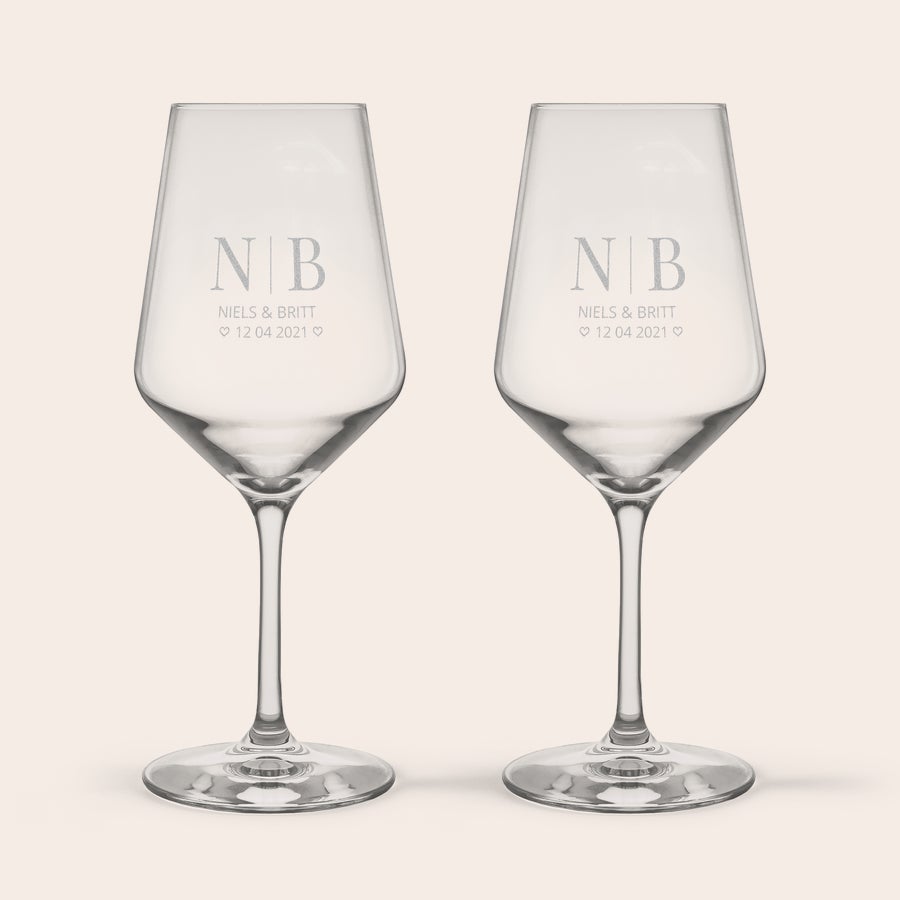 Rode wijnglazen graveren Twee gepersonaliseerde kristallen wijnglazen, gegraveerd met de initialen NB, namen Niels & Britt, en datum 12.04.2023.