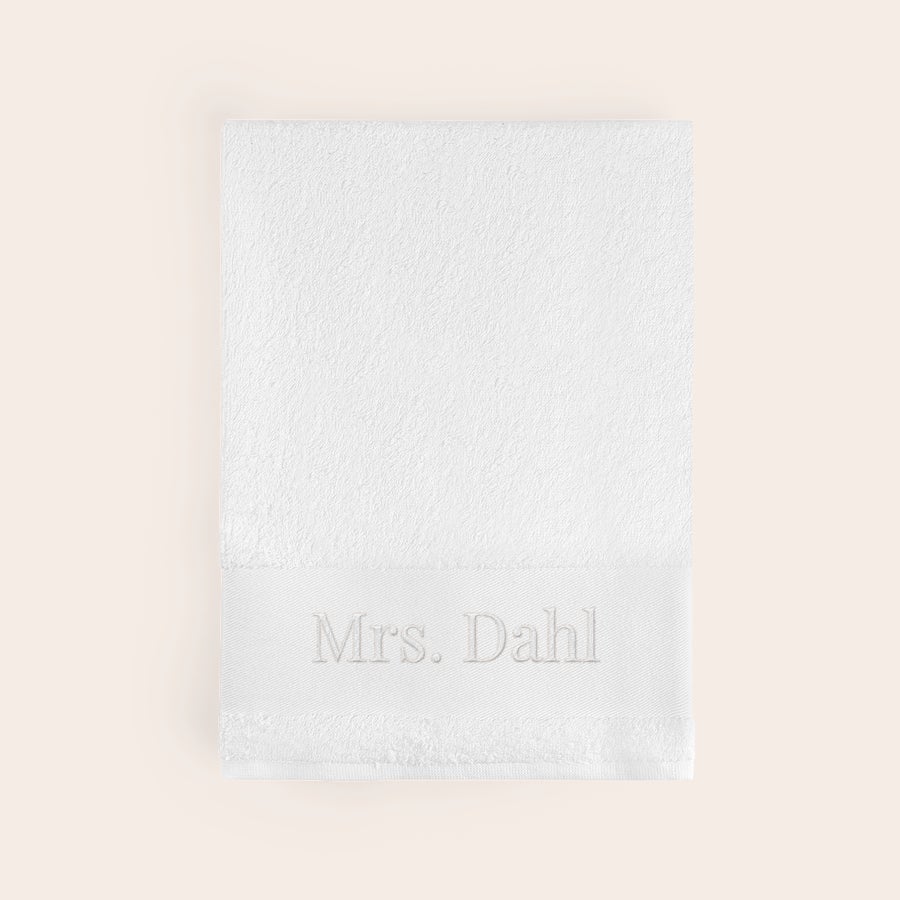 Badhandduk med text Vit personlig badhandduk i bomull, broderad med texten "Mrs. Dahl" i grått