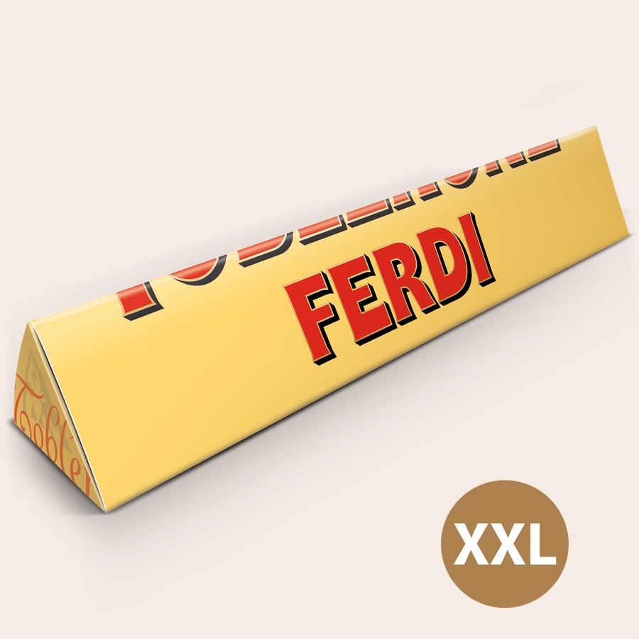 Toblerone XXL bedrukken Gepersonaliseerde XXL Toblerone reep met de naam 'Ferdi' op de wikkel bedrukt. Deze persoonlijke XXL Toblerone reep is echt een MEGA grote verrassing.