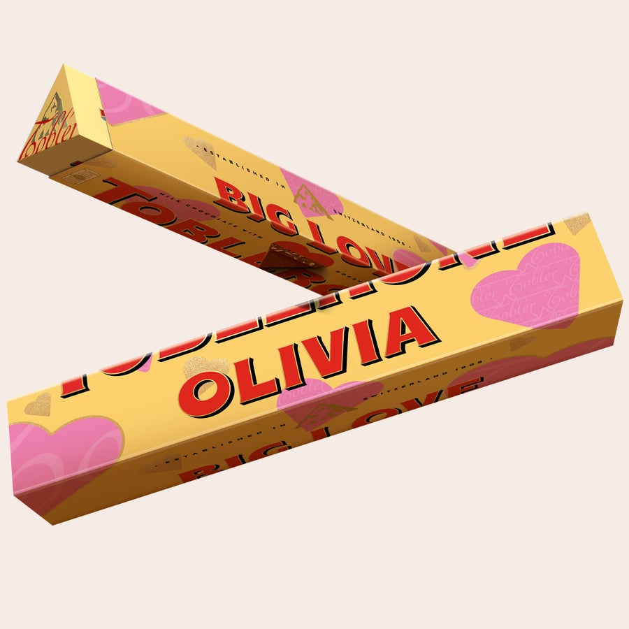Toblerone csokoládé - Szerelem Személyre szabott Toblerone csokoládé sárga csomagolásban Olivia névvel, rózsaszín szívekkel és méz-mandula nugáttal