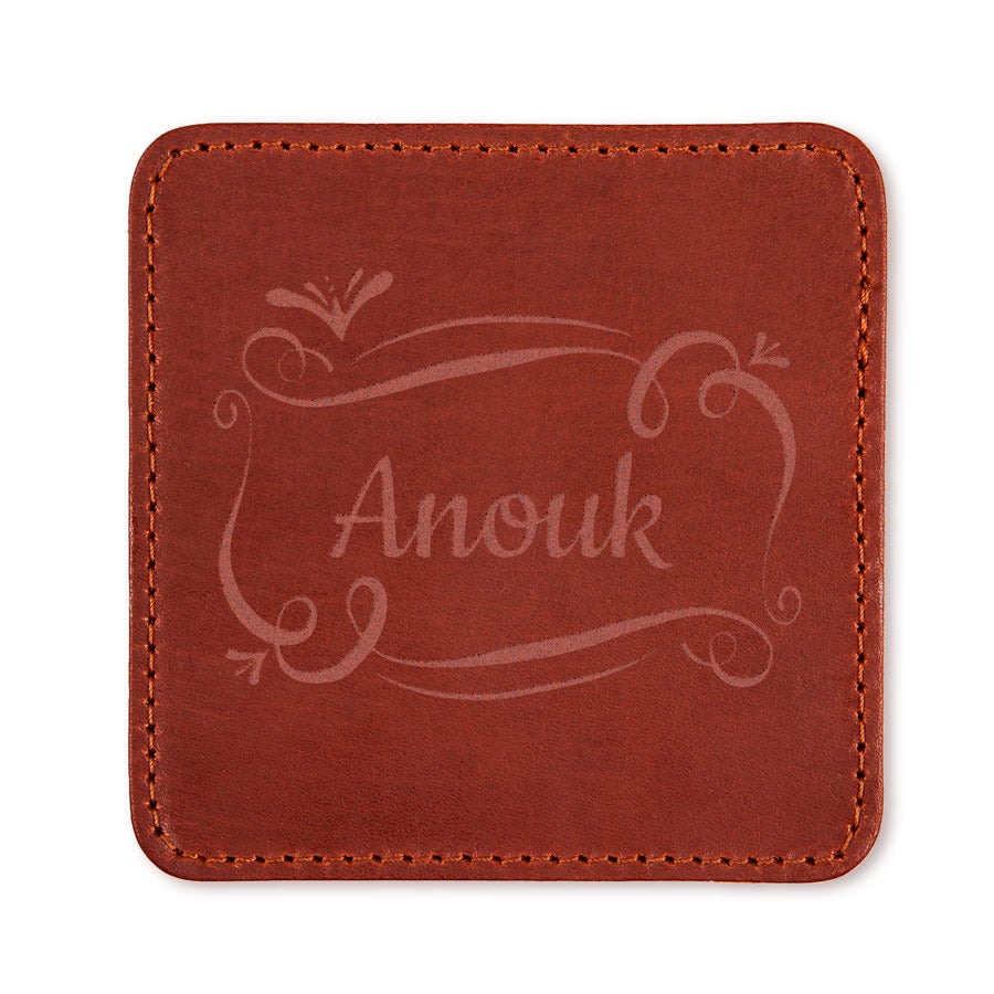 Leren onderzetter - Bruin, gegraveerd met de naam Anouk in sierlijke letters en decoratieve krullen.