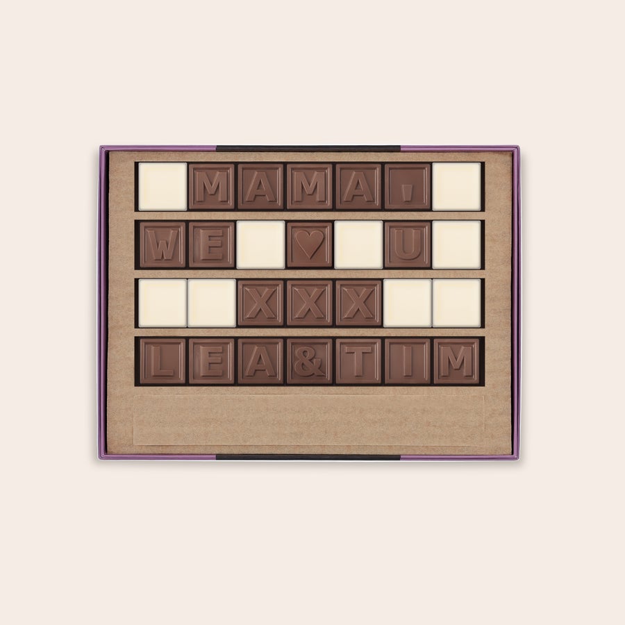 Schokotelegramm Selber Gestalten Milchschokoladen Chocotelegramm mit der Nachricht "MAMA WE ♡ U XXX LEA & TIM" und weißen Schokoladenstückchen als Leerzeichen in einer Geschenkbox, genieße ein persönliches Schokoladentelegramm mit deiner persönlichen Nachricht.