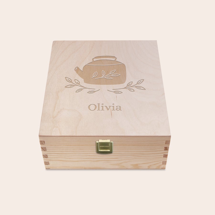Fa gravírozott teásdoboz Világos fa teásdoboz gravírozott teáskanna motívummal és "Olivia" felirattal a fedelén, fémkapoccsal.
