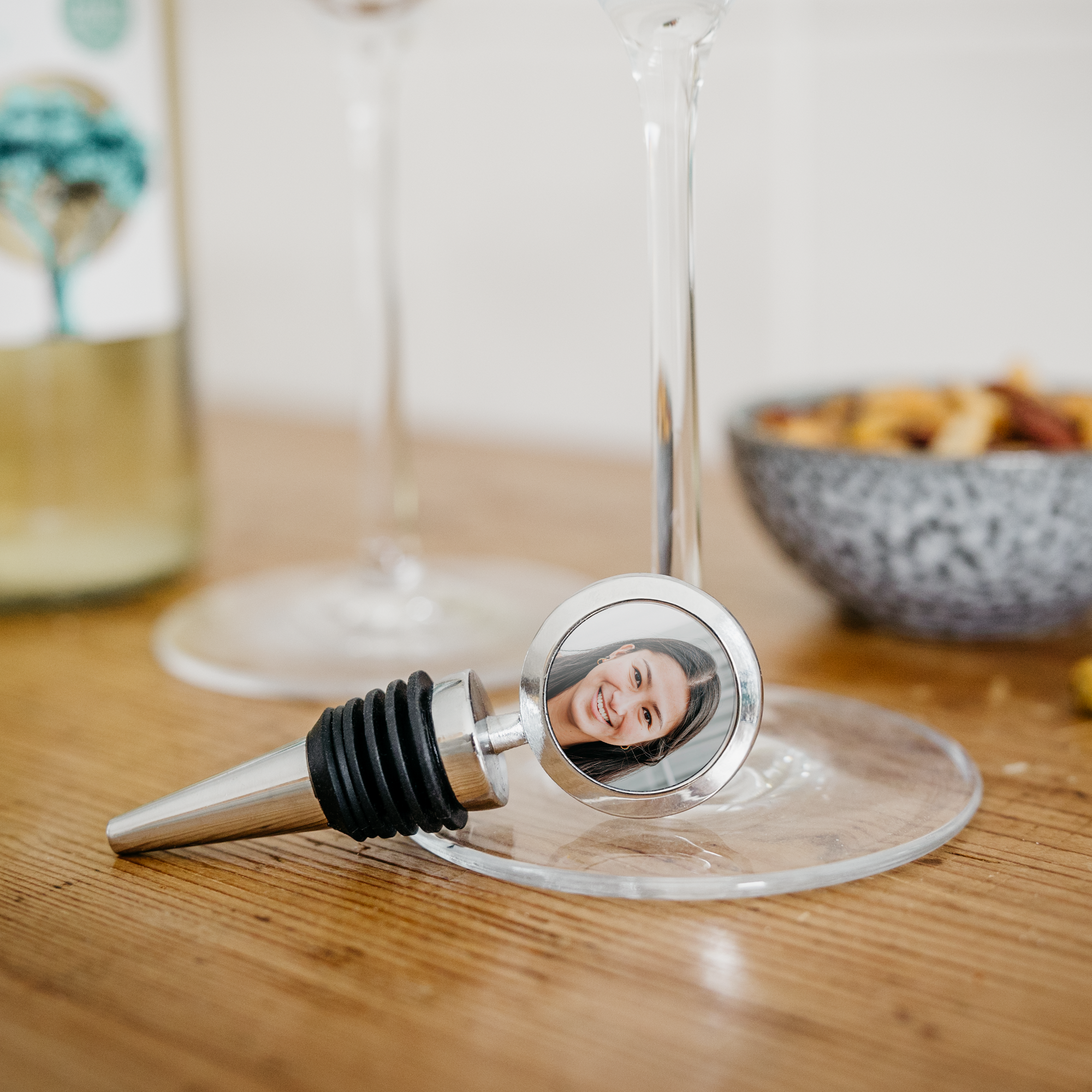 Sølvfarvet vinprop med et foto af en smilende kvinde trykt på toppen, personlig vinprop