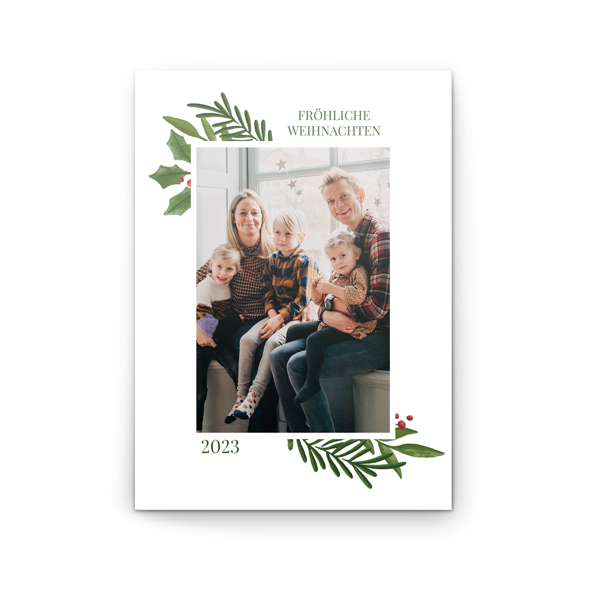 Personalisierte Fotokarte Frohe Weihnachten 2023 mit einem Familienfoto, gedruckt auf matter Oberfläche, verziert mit grünen Blättern und roten Beeren.