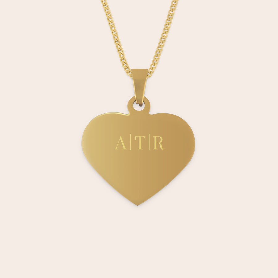 Herzanhänger mit Gravur Ein goldener herzförmiger Anhänger, graviert mit dem Namen "ATR", bietet ein tolles Geschenk.