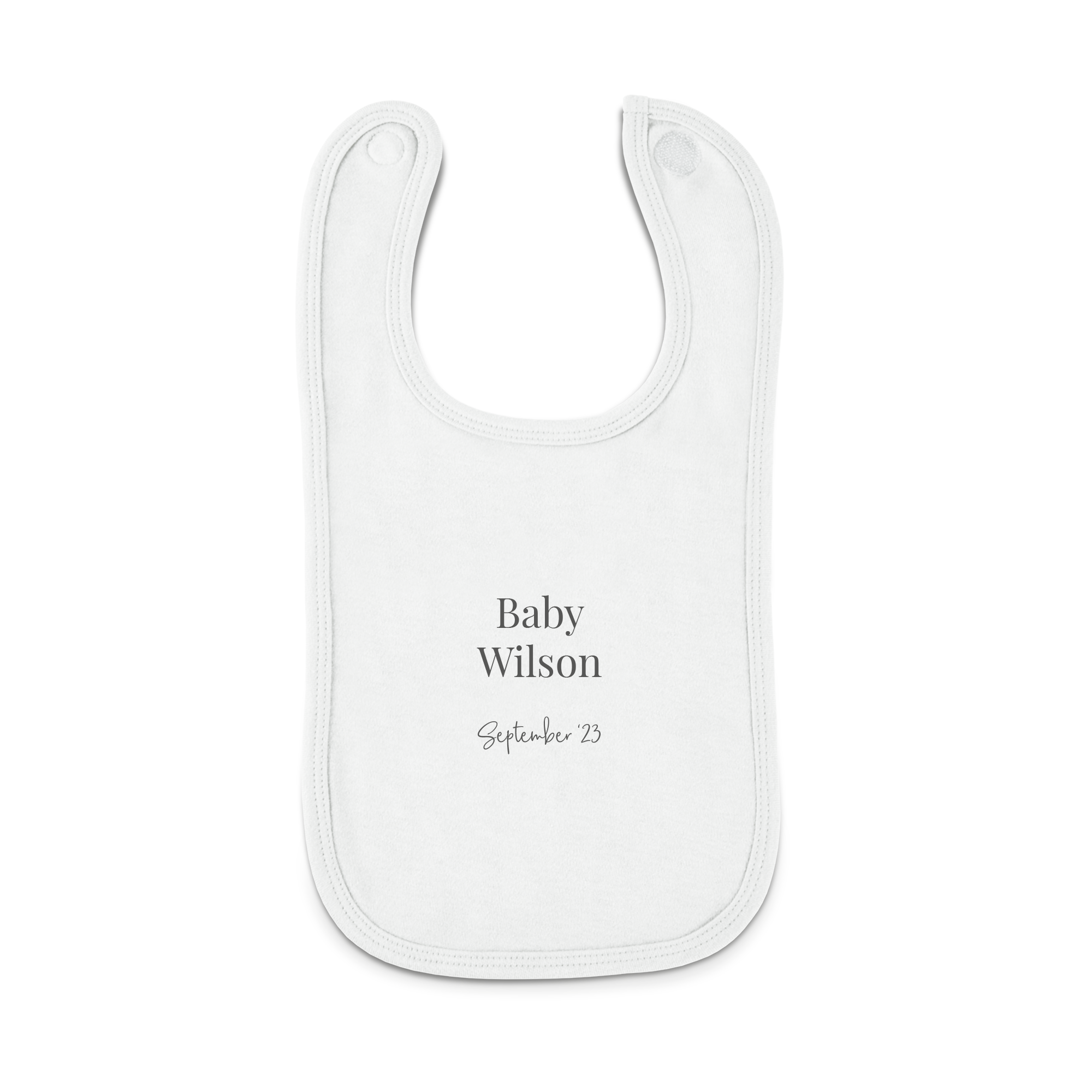 Babero personalizado blanco con el texto "Baby Wilson September '23" impreso en el centro, ideal para regalo.