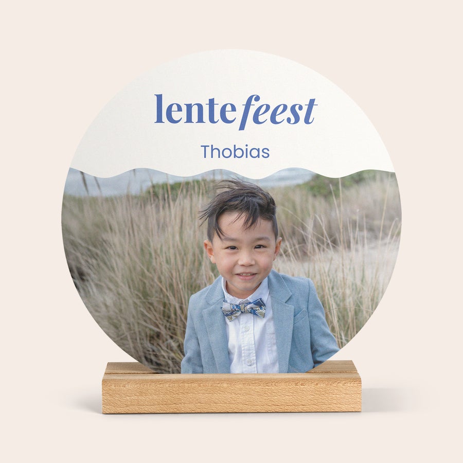 Lesena plošča s fotografijo Okrogla lesena foto ploščica s personalizirano fotografijo fanta, imenom Thobias in napisom lentefeest, na lesenem stojalu.