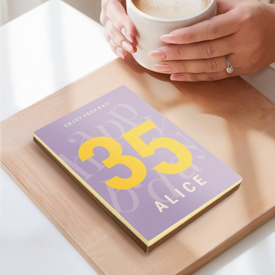 Chocolate Letter Personalized chocolate letter with "35" and "Alice" printed, next to a person holding a coffee mug.