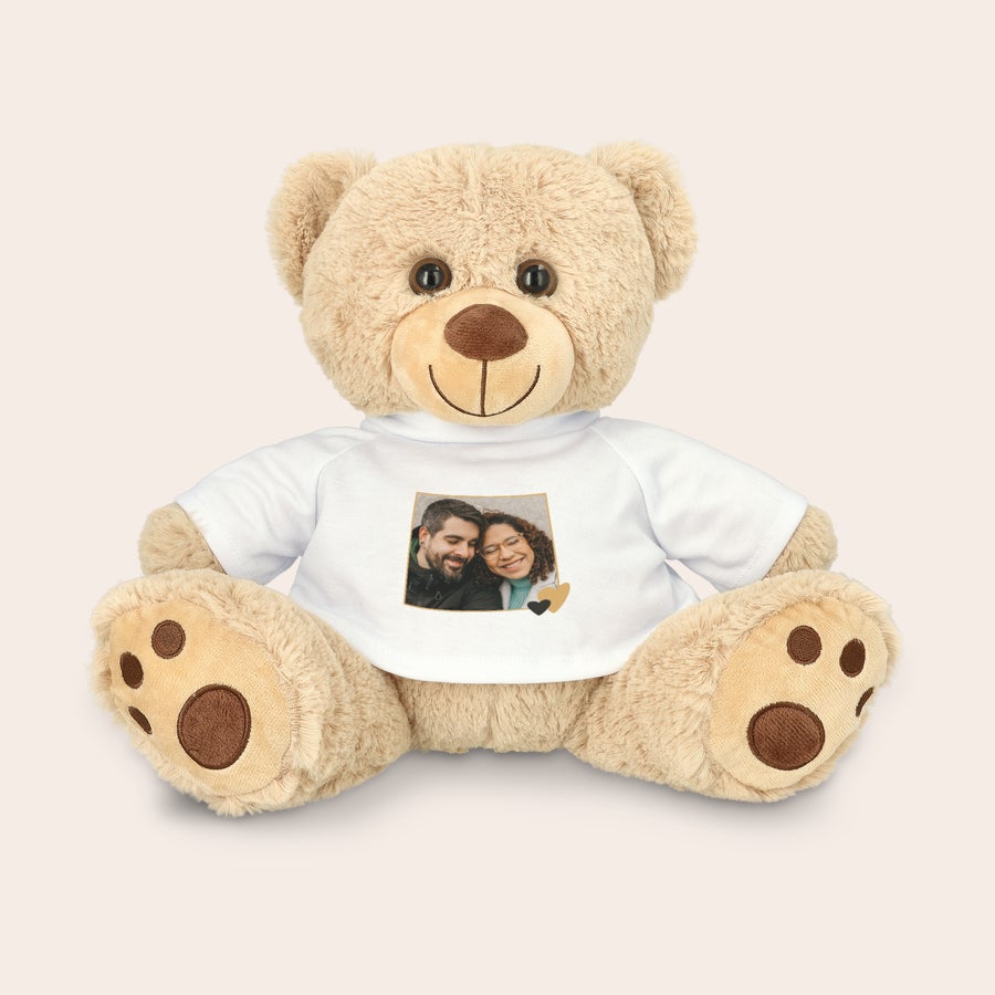 Personalised cuddly toy bear A teddy bear wearing a white T-shirt printed with a custom photo of a couple to surprise them.