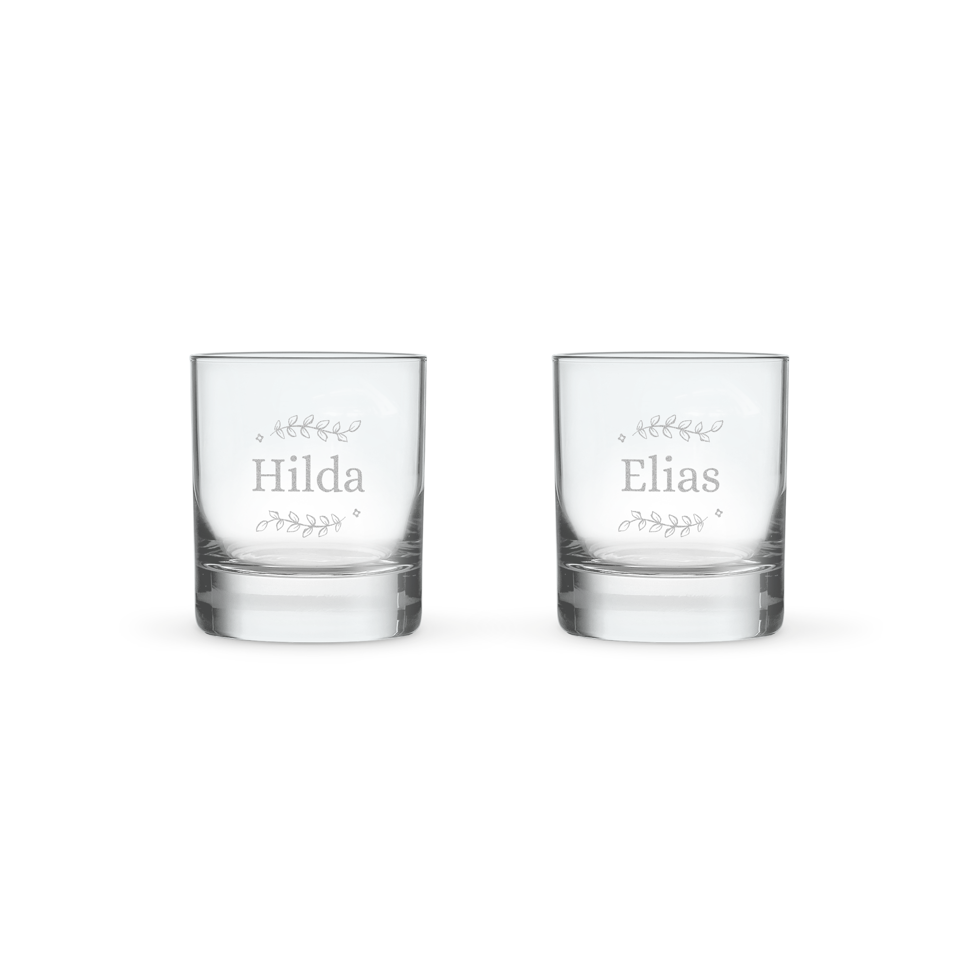 Två graverade whiskyglas i presentset med personliga namn, "Hilda" och "Elias", omgivna av löv.