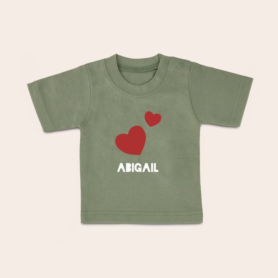 Tricou personalizat - Bebeluș Cămașă veselă pentru bebeluș personalizată, de culoare verde măsliniu, imprimată cu două inimi roșii și numele Abigail.