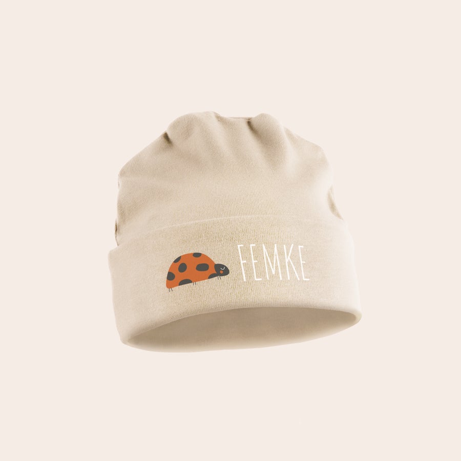 Babymuts Schattig bedrukt babymutsje in beige met een liefheersbeestje en de naam 'FEMKE'.