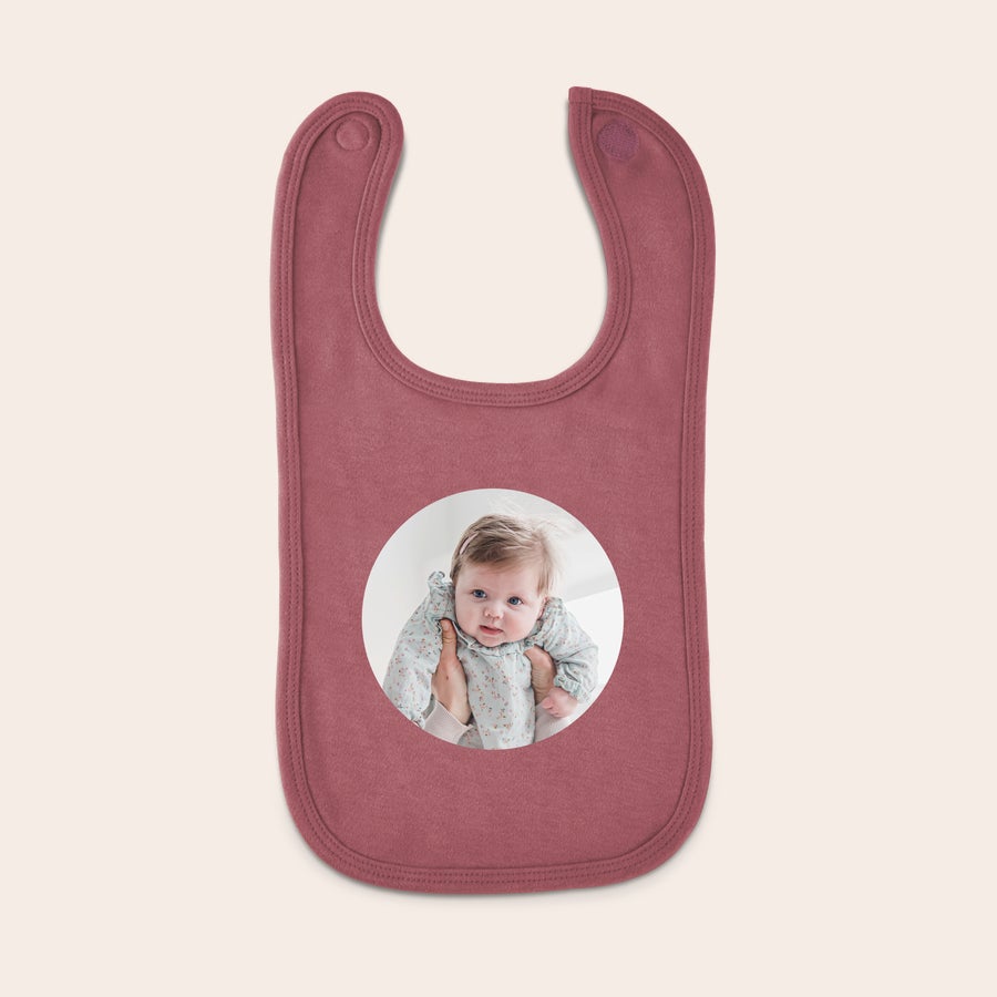 Slabbetje bedrukken Oudroze slabbetje met klittenbandsluiting, bedrukt met een foto van een baby. Knoeien wordt een feestje met een persoonlijk bedrukt slabbetje.