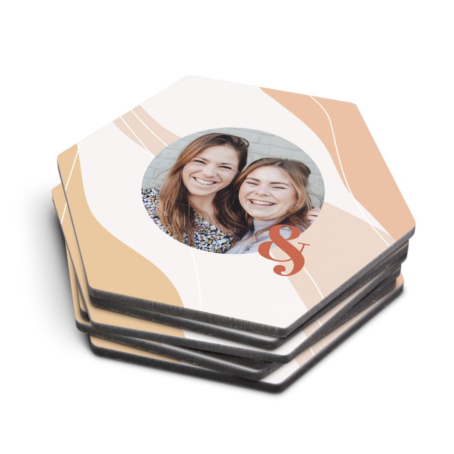 Posavasos personalizados hexagonales impresos con foto de dos mujeres sonriendo y una "y" estilizada.
