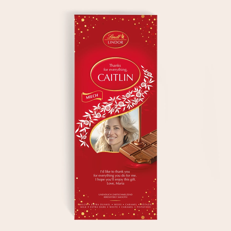 XL Lindor čokoladna ploščica XL Lindor čokoladno darilo z natisnjeno osebno fotografijo in imenom Caitlin, na rdeči embalaži z zlatimi pikami.
