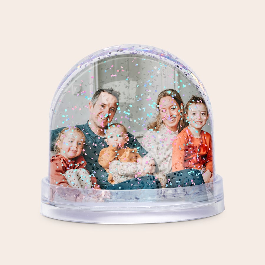 Snöglob Personifierad snöglob med en familjebild och färgglatt glitter som virvlar runt, redo att överraska.