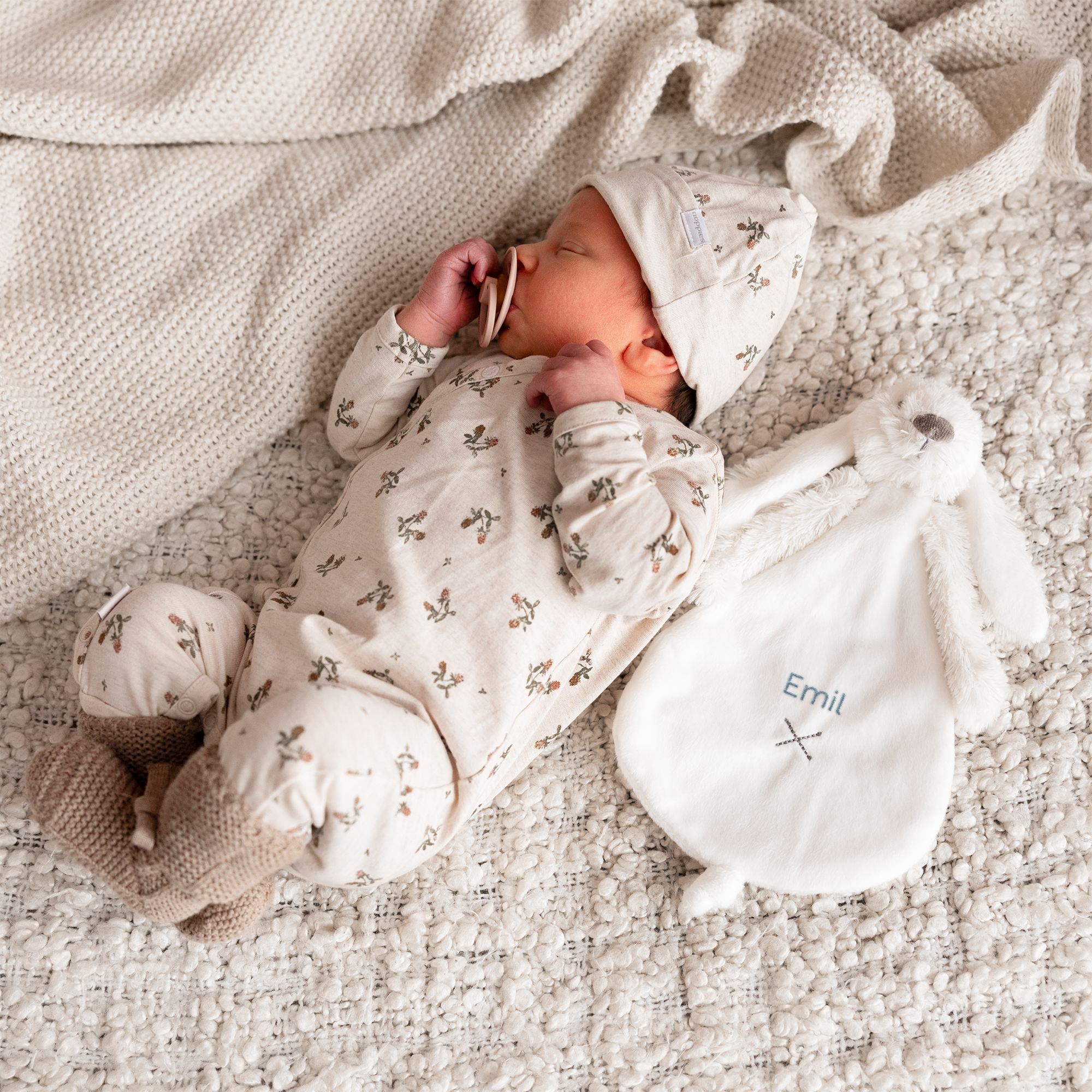 Søt hvit Rabbit Richie kosekanin med brodert navnet Emil, ved siden av en sovende baby.