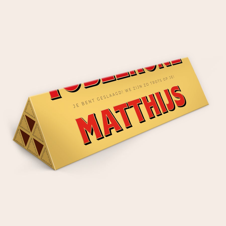 Toblerone met naam Toblerone reep met naam - 1800 gram. Gepersonaliseerde Toblerone reep in goud met de naam Matthijs en de tekst Je bent geslaagd!