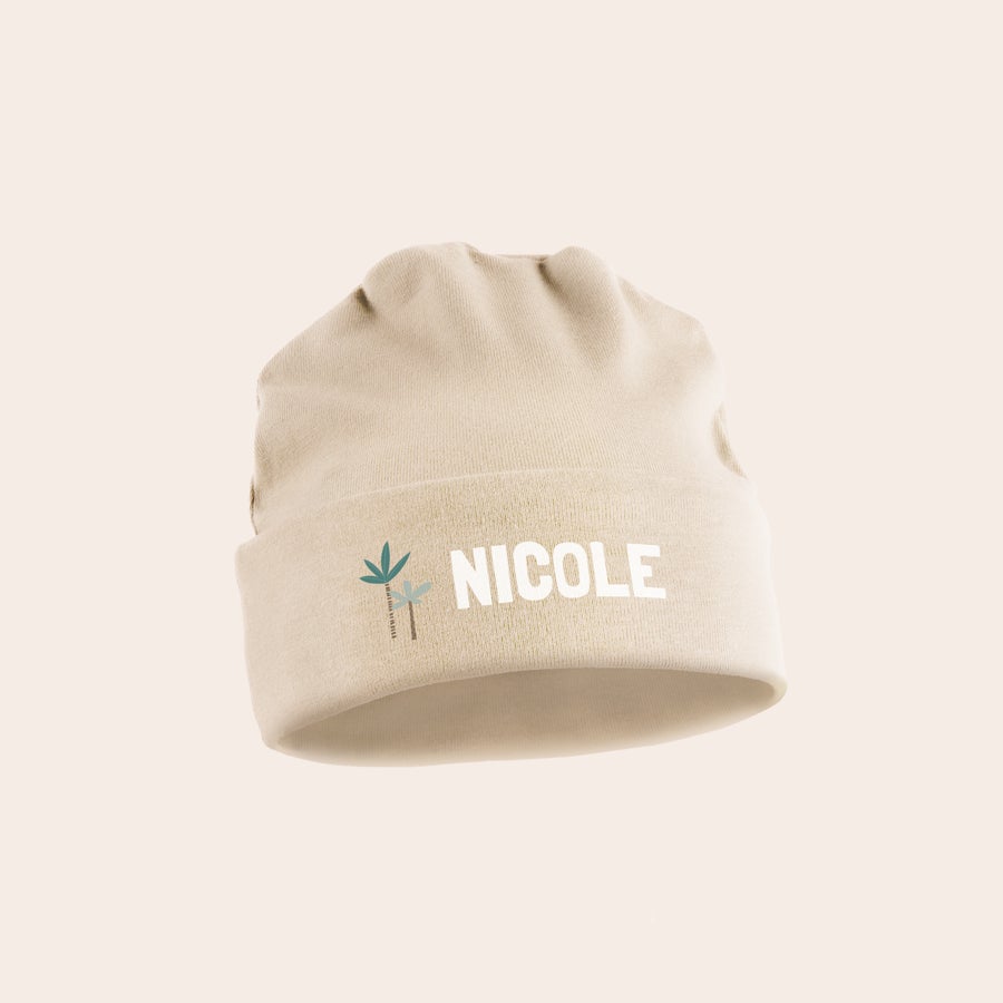 Bonnet naissance personnalisé Mignon bonnet bébé personnalisé couleur sable avec le prénom Nicole imprimé et deux palmiers.