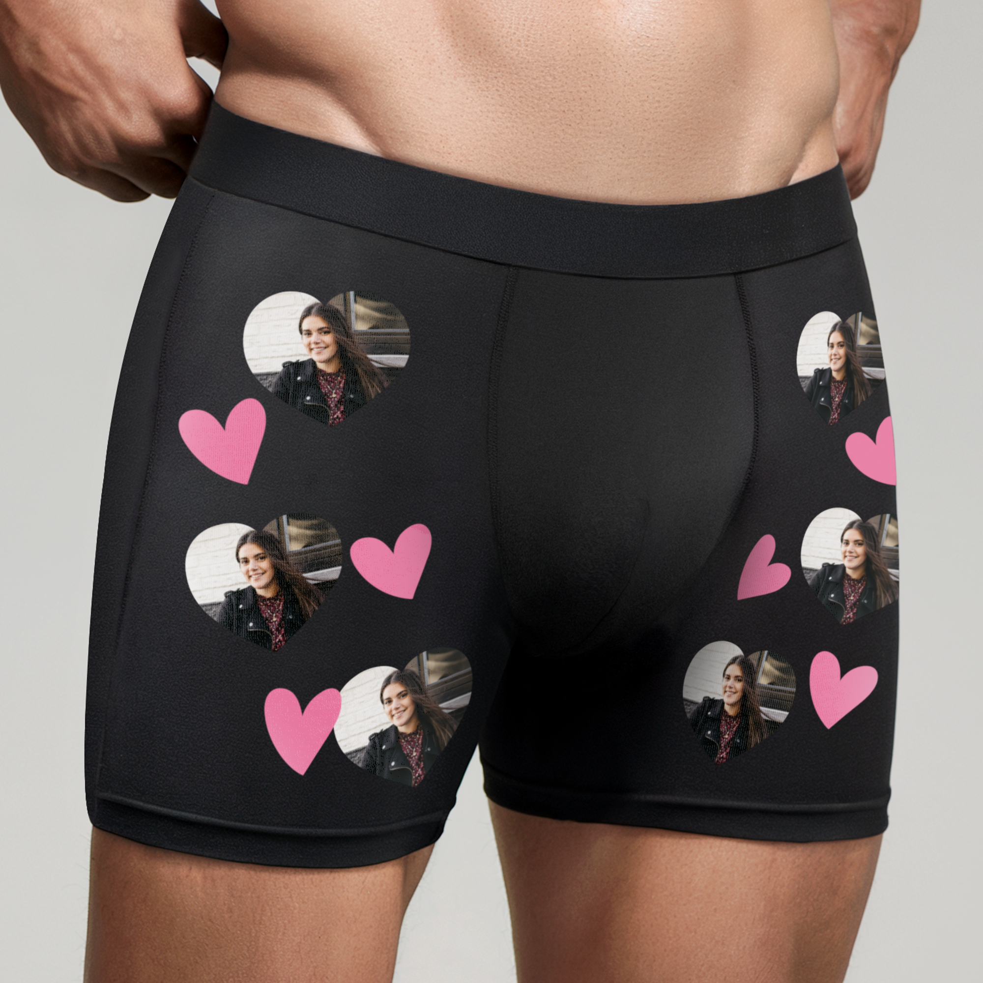Black personalised boxer shorts for him, printed with multiple heart-shaped photos of a woman and pink hearts