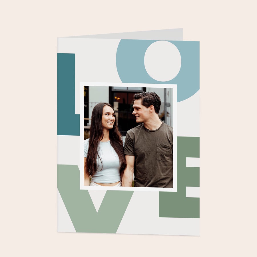 Card foto personalizat Carte foto personalizată cu o imagine imprimată a unui cuplu, pe un design cu text LOVE stilizat în culori pastelate.