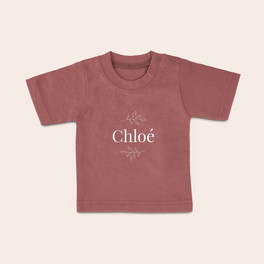 Baby shirt bedrukken Een roze baby shirt met naam Chloé en blaadjes, bedrukt met tekst.