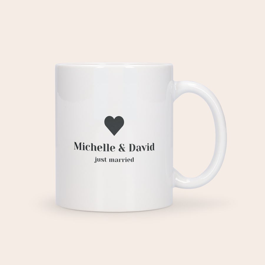 Cană de dragoste personalizată - ediție specială Cană albă personalizată cu inimă, numele Michelle & David și textul just married tipărite.