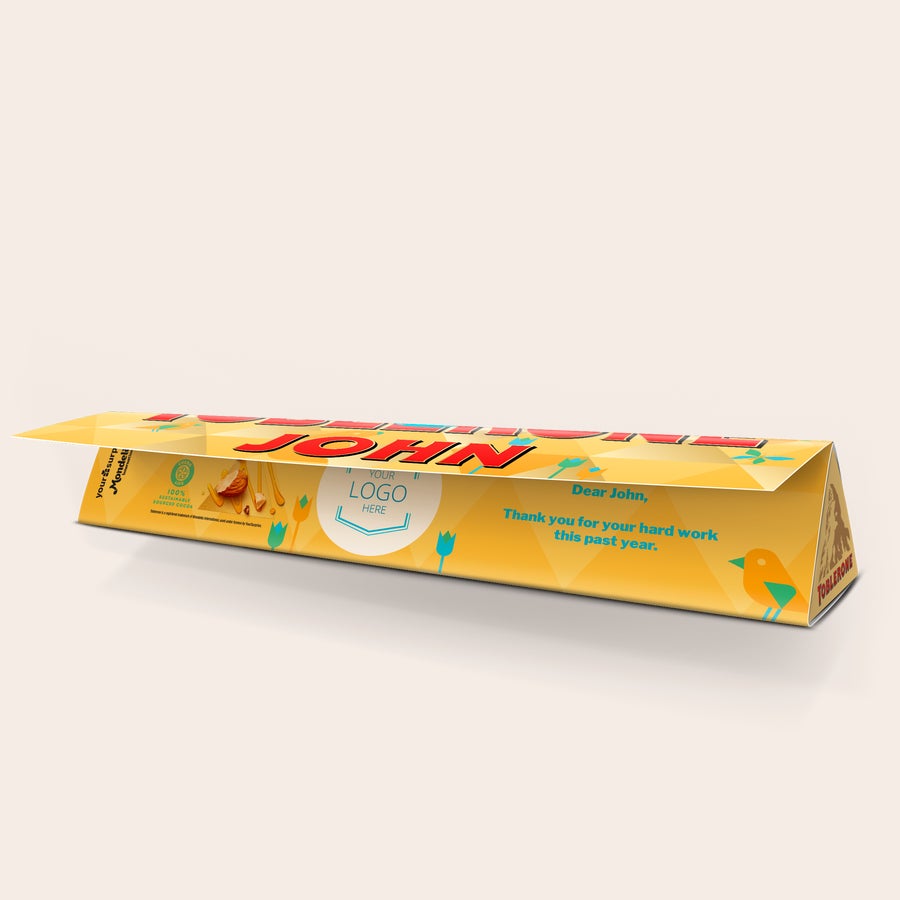Toblerone Personalizado - Pascua Barra de chocolate personalizada de Toblerone para Pascua, con envoltura amarilla impresa con el nombre John y mensaje, un logo y un diseño de pascua.