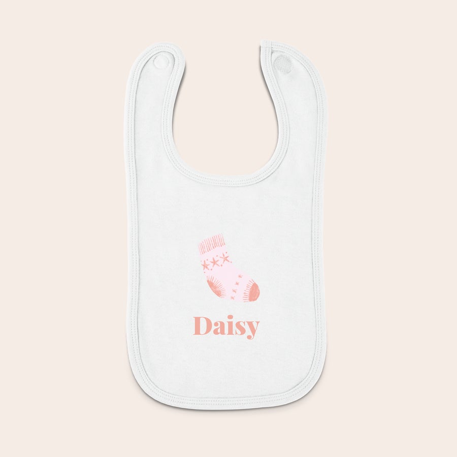Babero personalizado - Primera Navidad - Blanco Babero personalizado blanco para bebé con estampado de calcetín rosa y el nombre Daisy