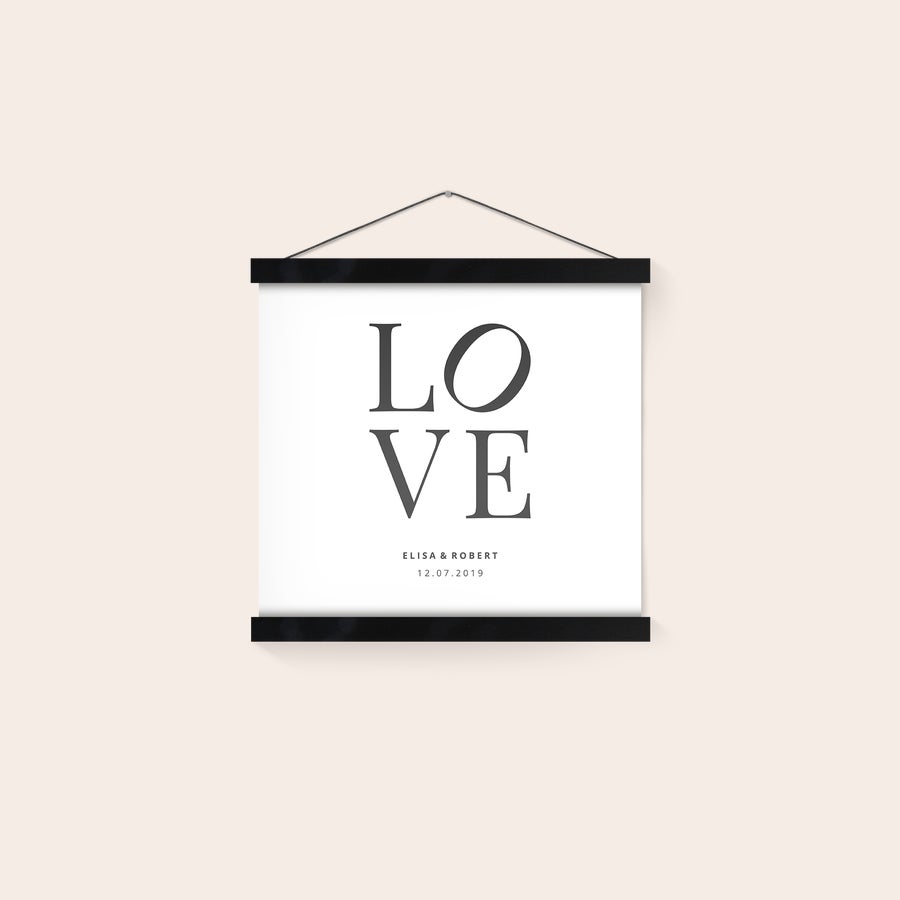 Poster personaliseren met posterhanger Gepersonaliseerde fotoposter met de tekst "LOVE" en de namen Elisa & Robert, 12.07.2019, hangend in een zwarte magnetische posterhanger.