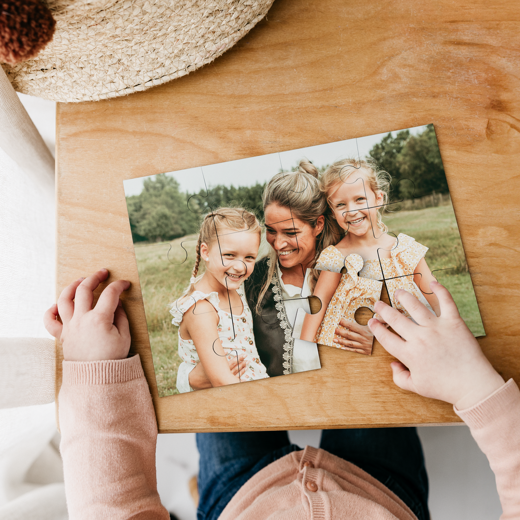 Child's hands assembling a photo puzzle, personalized with a family image of a mother and two young daughters