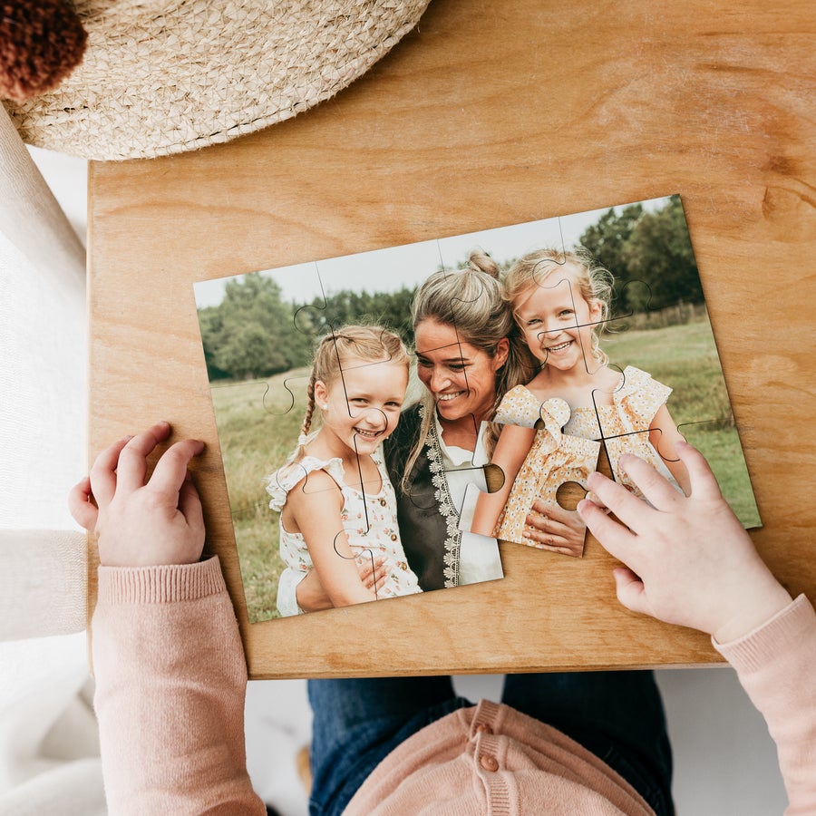 Personalised puzzle - Small Child's hands assembling a photo puzzle, personalized with a family image of a mother and two young daughters