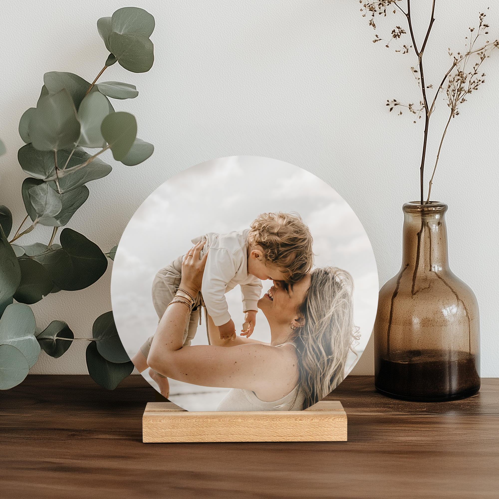 Mosaico fotográfico redondo de madera con una foto impresa de una madre y su bebé, incluye soporte.