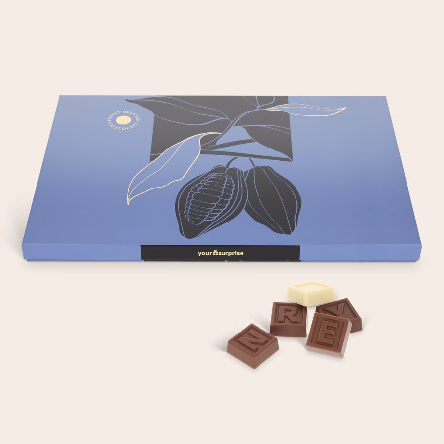 Telegrama de ciocolată personalizată Cutie albastră cu ilustrație cacao, conținând o telegramă personală de ciocolată cu litere individuale din ciocolată cu lapte și albă.