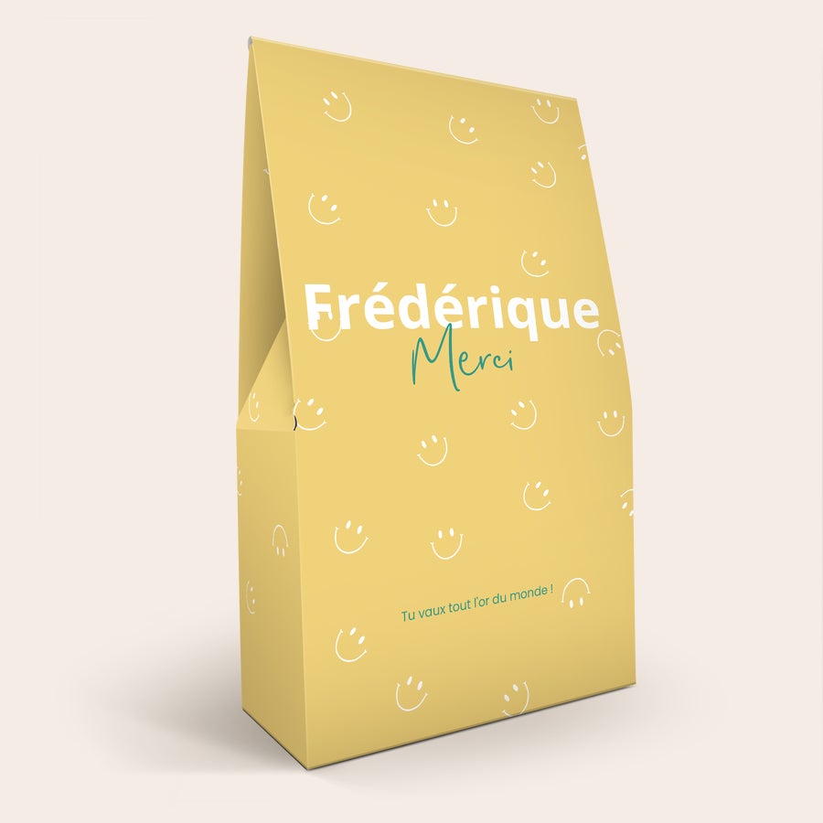 Coffret cadeau Haribo XL Coffret cadeau XL de bonbons Haribo personnalisé avec le nom "Frédérique Merci" et le message "Tu vaux tout l'or du monde", imprimé sur une boîte jaune décorée de smileys blancs.