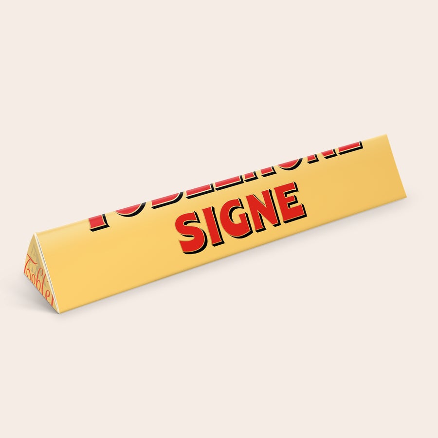 Toblerone med navn Personaliseret Toblerone med navn og billede, trykt med navnet SIGNE på en gul indpakning.